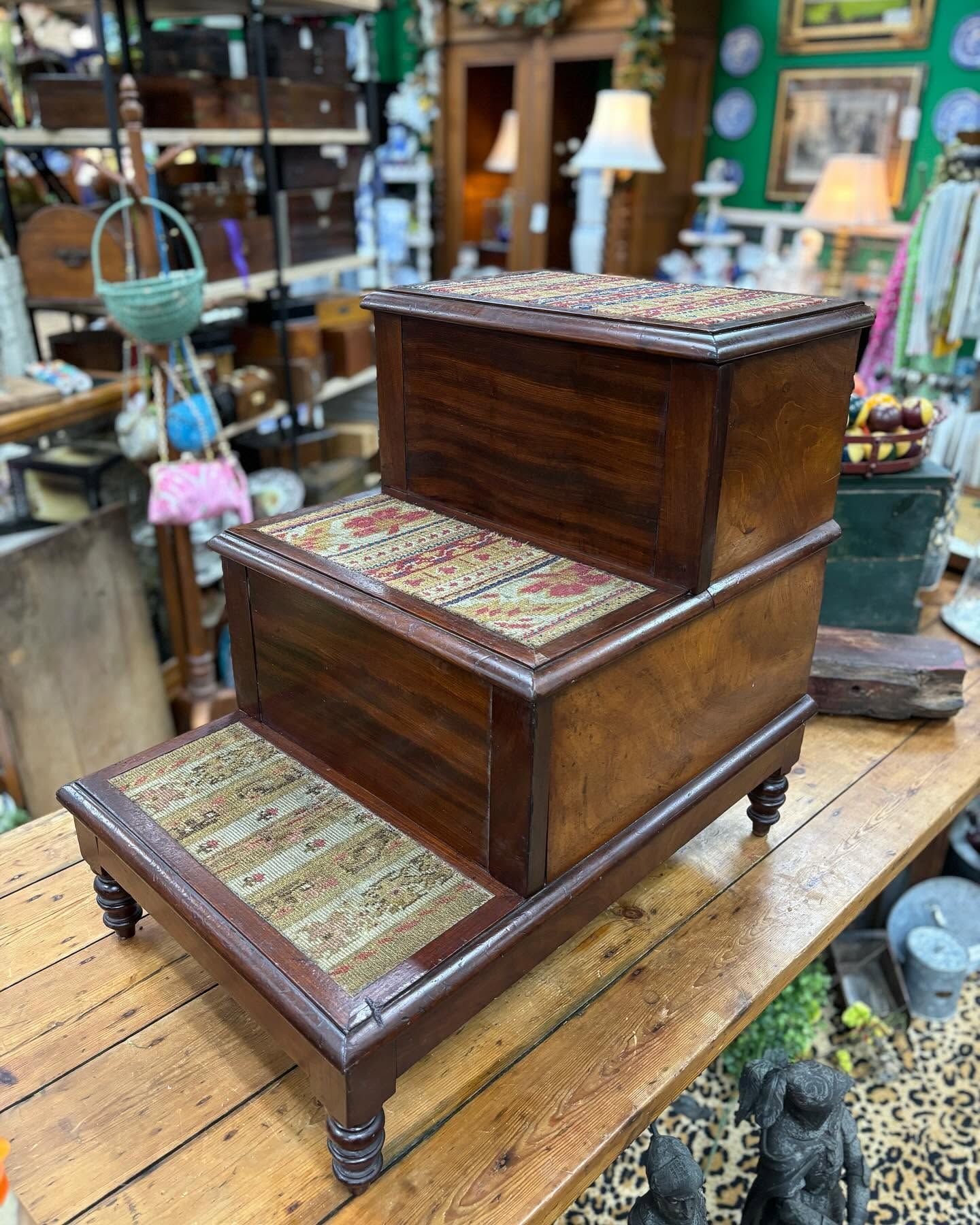 Three-tier wooden display step with patterned tile tops in a shop
