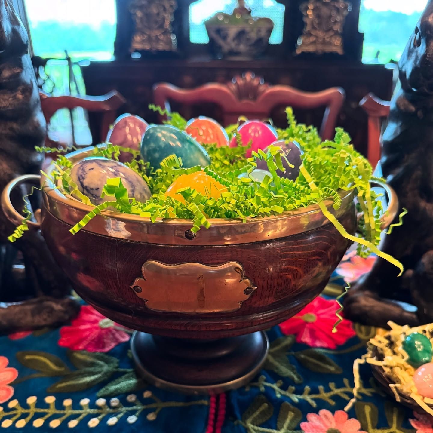 Decorative bowl of colorful painted eggs and greenery on a dining table centerpiece