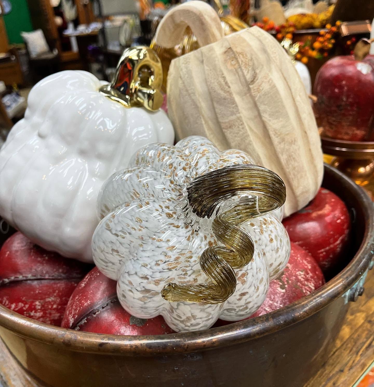 Decorative white and gold pumpkins with red apples in a metal bowl