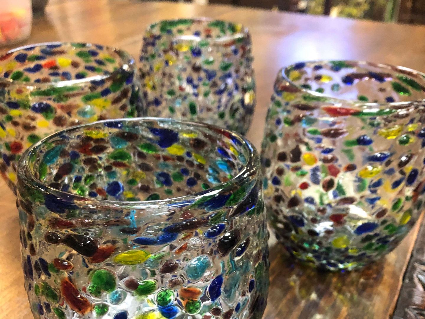 Colorful speckled glass candle holders on a wooden surface, with one in the foreground.