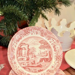 Red and white decorative holiday plate beside a Christmas tree and candles