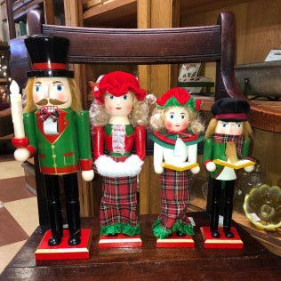Four Christmas nutcracker dolls in green, red, and black standing on a chair indoors