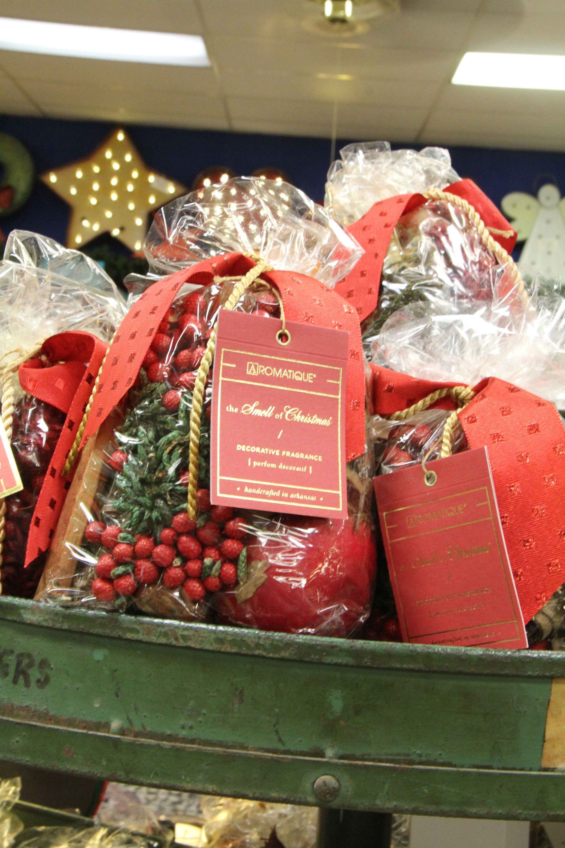 Holiday gift baskets wrapped in red cellophane with decorative tags on a green cart