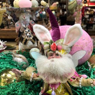 Decorative bunny figurine with white fur, pink ears, and a flower crown, set among Easter ornaments