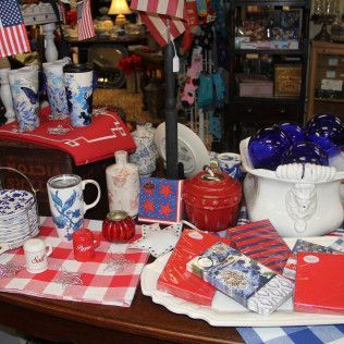Assorted red, white, and blue patriotic tableware and gifts displayed on a table with checkered cloth.