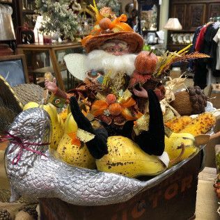 Decorative Thanksgiving display with a Santa figure, pumpkins, and a silver turkey centerpiece in a store.