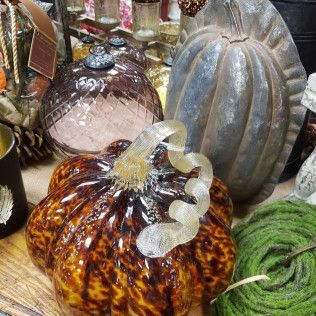 Decorative glass pumpkins in amber, clear, and gray on a market display