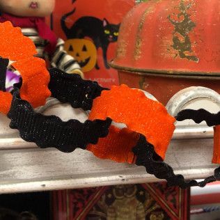 Orange and black Halloween garland draped over a white shelf with festive decorations behind it