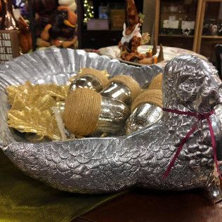 Decorative silver bowl filled with gold and silver ornaments, tied with a red ribbon