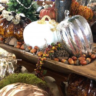 Decorative arrangement of white and silver pumpkins with pinecones and autumn berries in a wooden tray