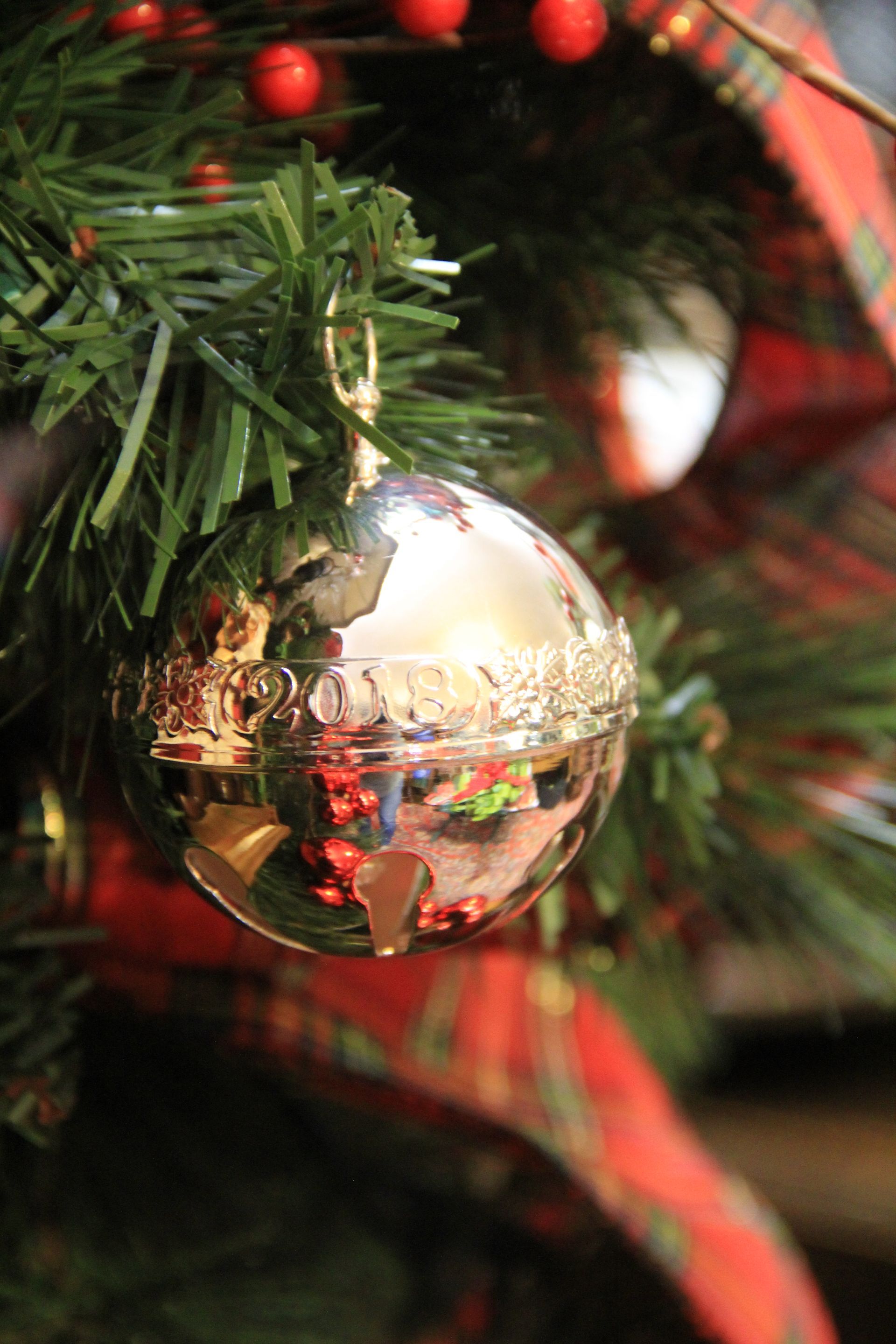 Gold Christmas ornament hanging on green pine branches with red decorations