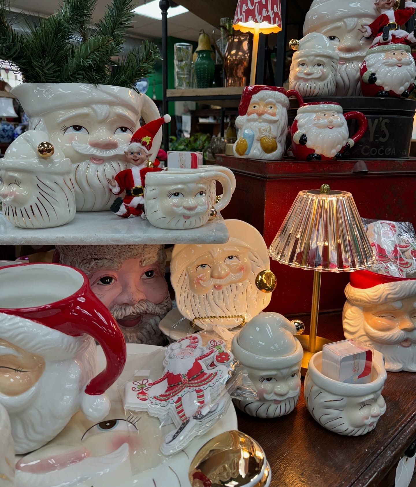 Santa-themed ceramic figurines and Christmas decor on display, with warm lamp light and a snowy holiday setting