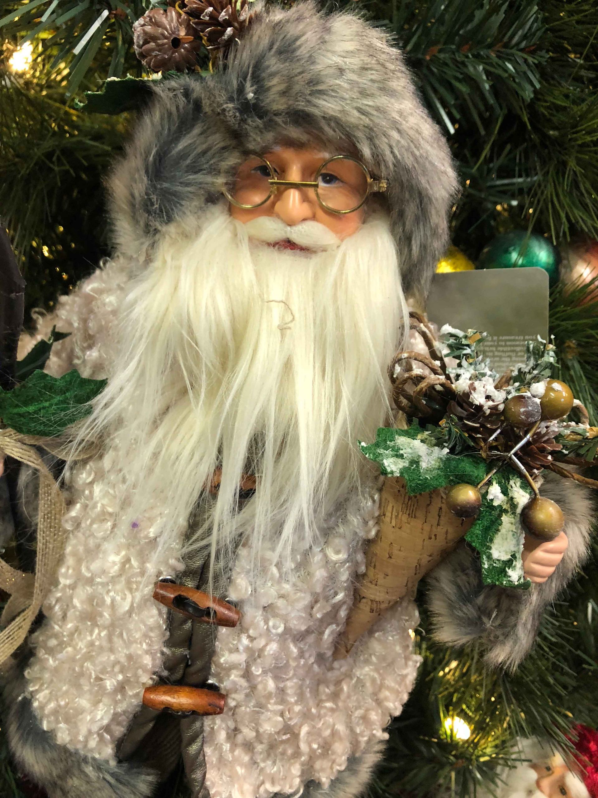 Santa figurine with a gray hat, white beard, and twinkling Christmas tree lights