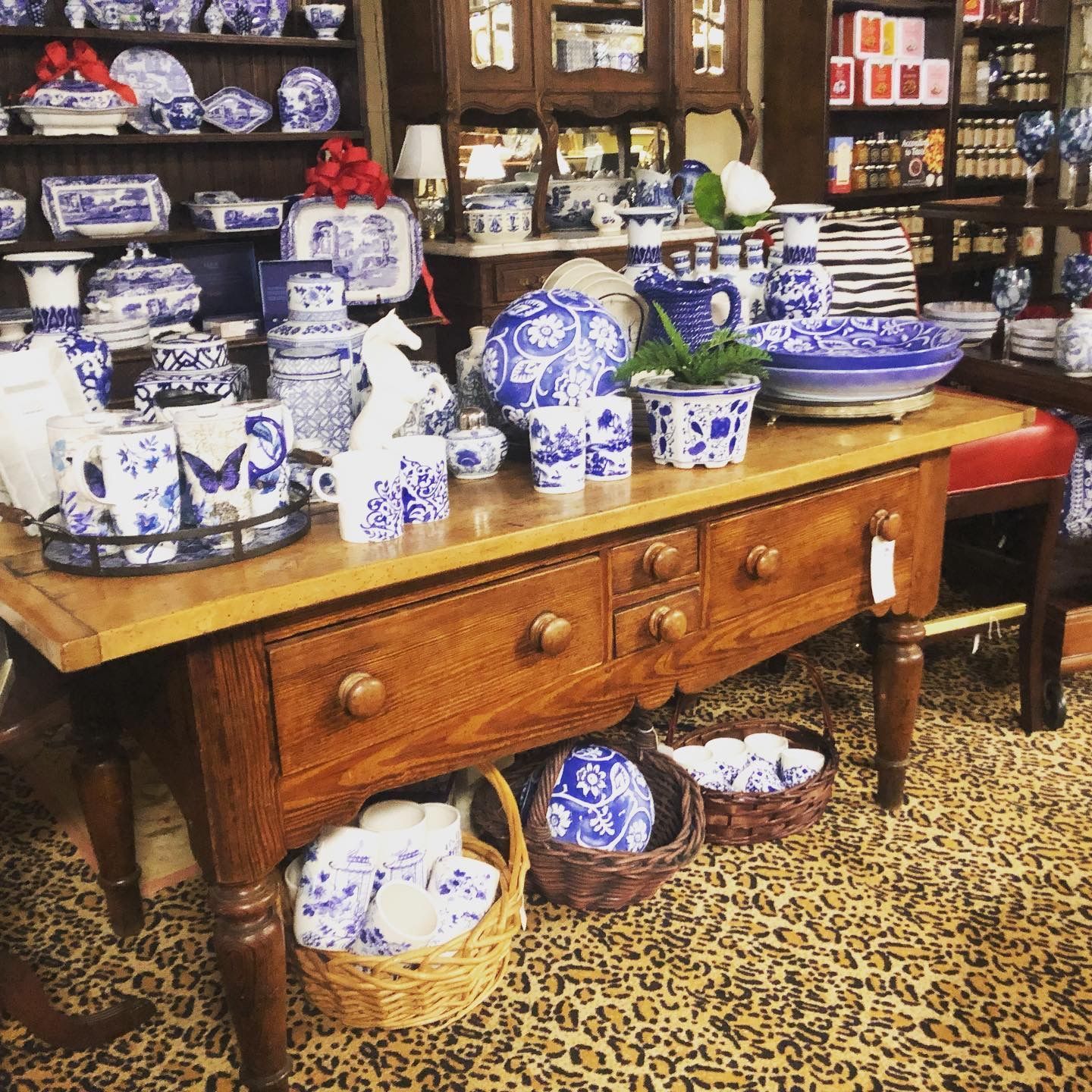Blue-and-white ceramic tableware displayed on a wooden table in a shop.