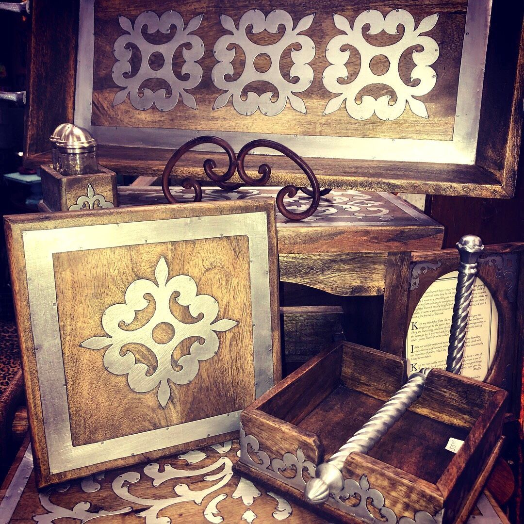 Decorative wooden boxes and trays with ornate white and gold floral patterns on a rustic table
