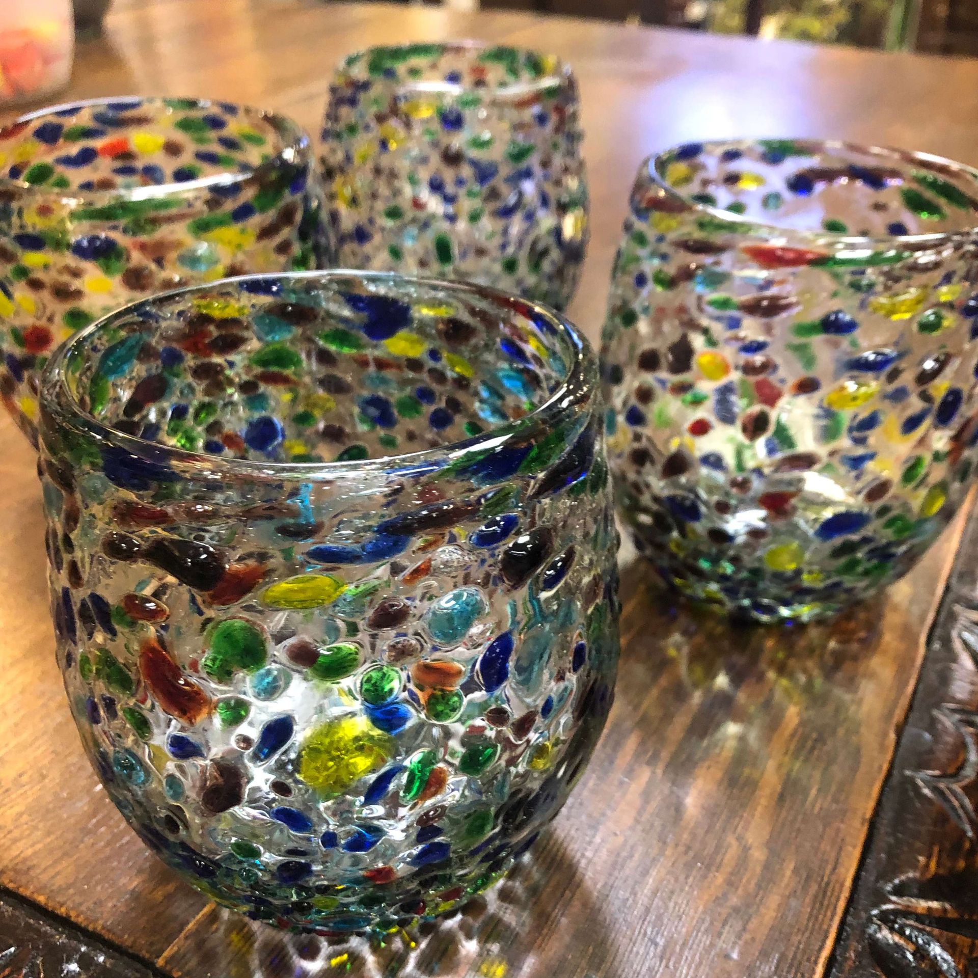Colorful speckled glass votive holders on a wooden tray
