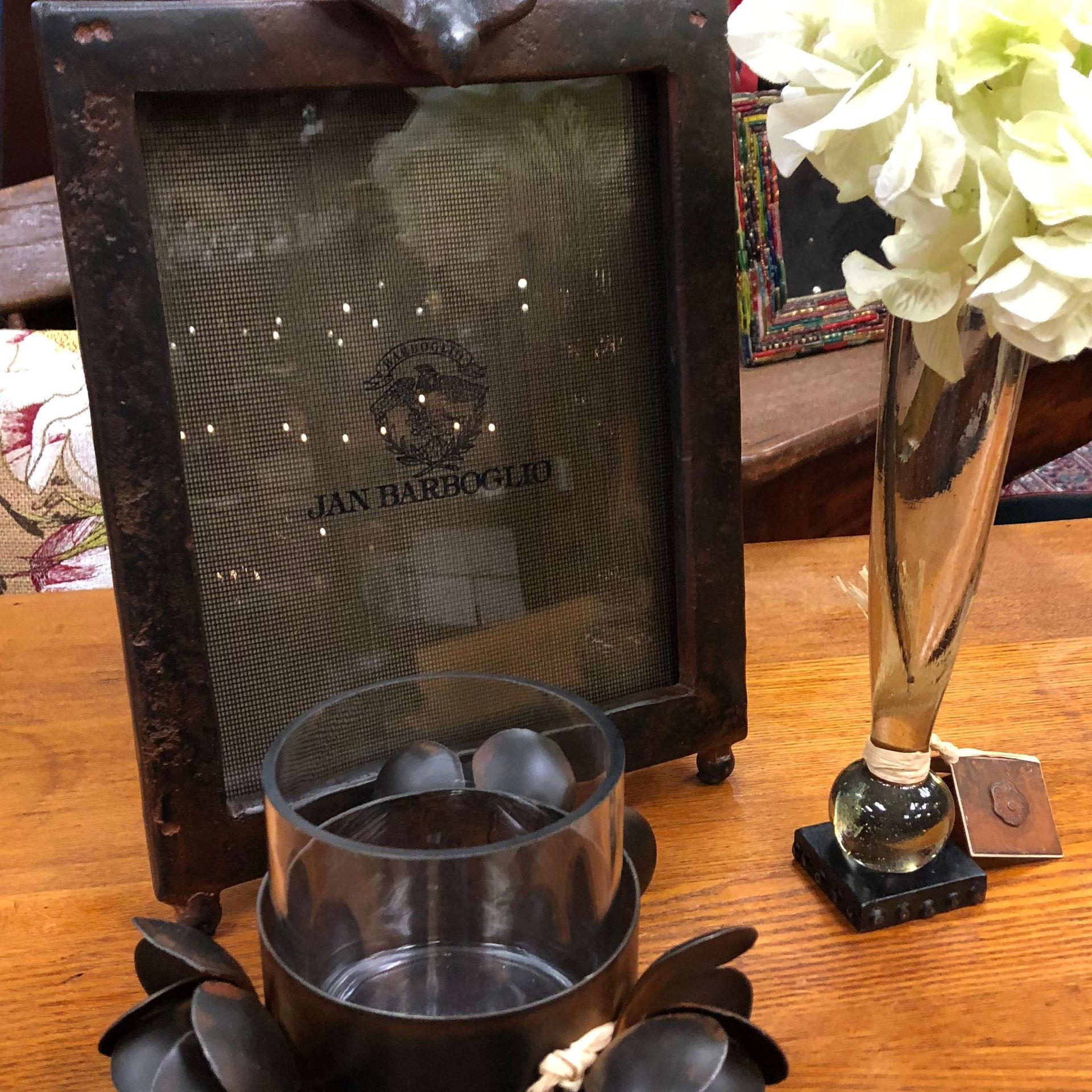 Glass trophy on a wooden table beside a vase of white flowers, with a candle holder in front.