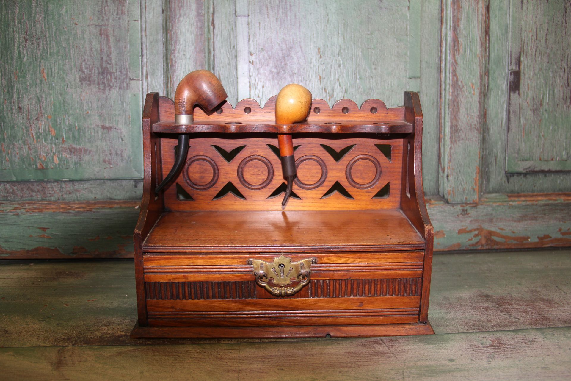 Small wooden chest with ornate carvings and apples on top, against a weathered green background