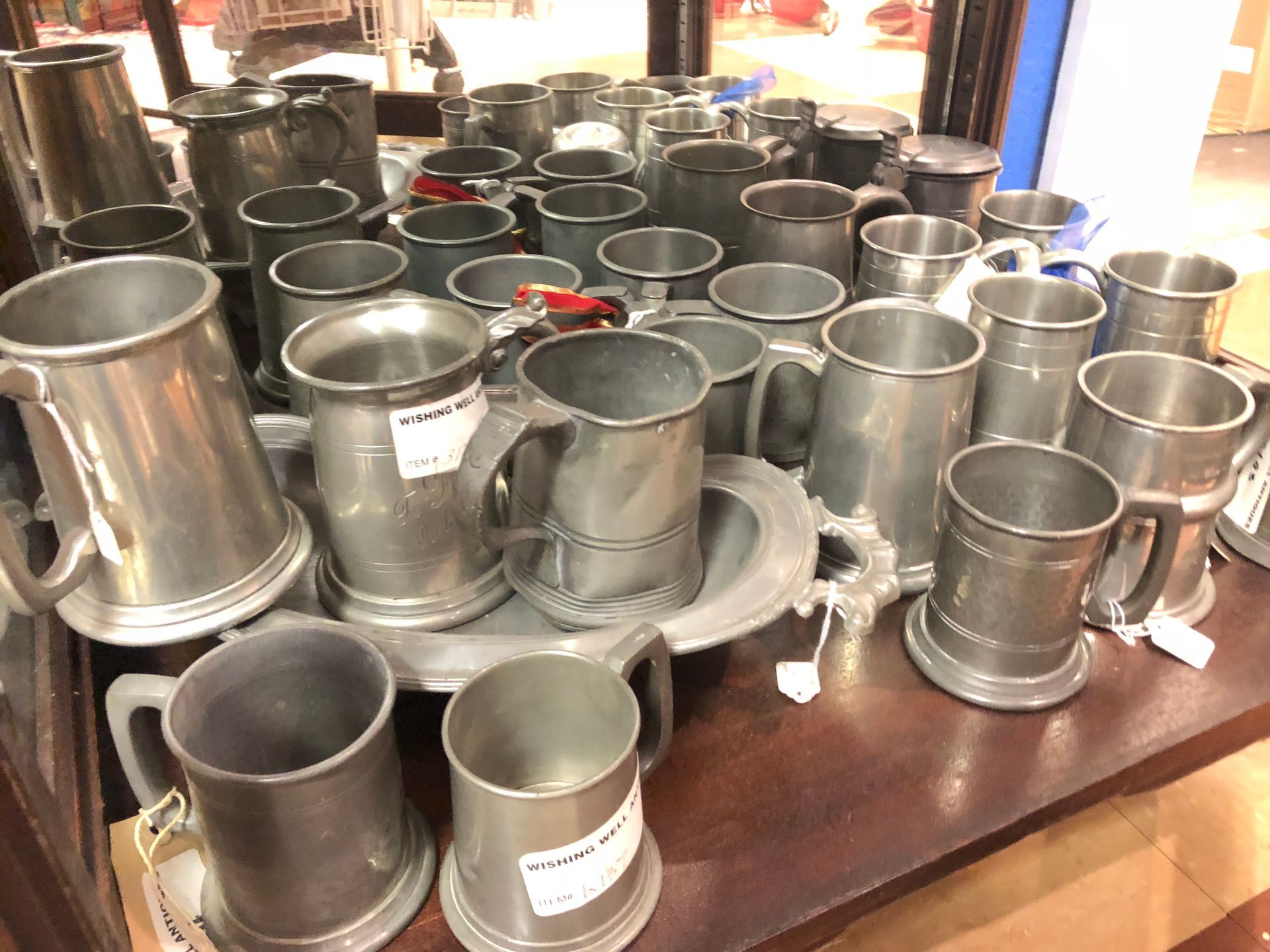 Assorted metal cups and mugs displayed on a wooden table in a shop