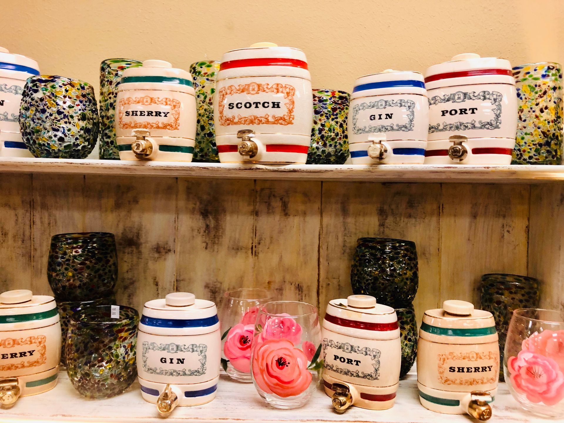 Wooden shelf with labeled jars of colorful herbal teas and pink rose decorations