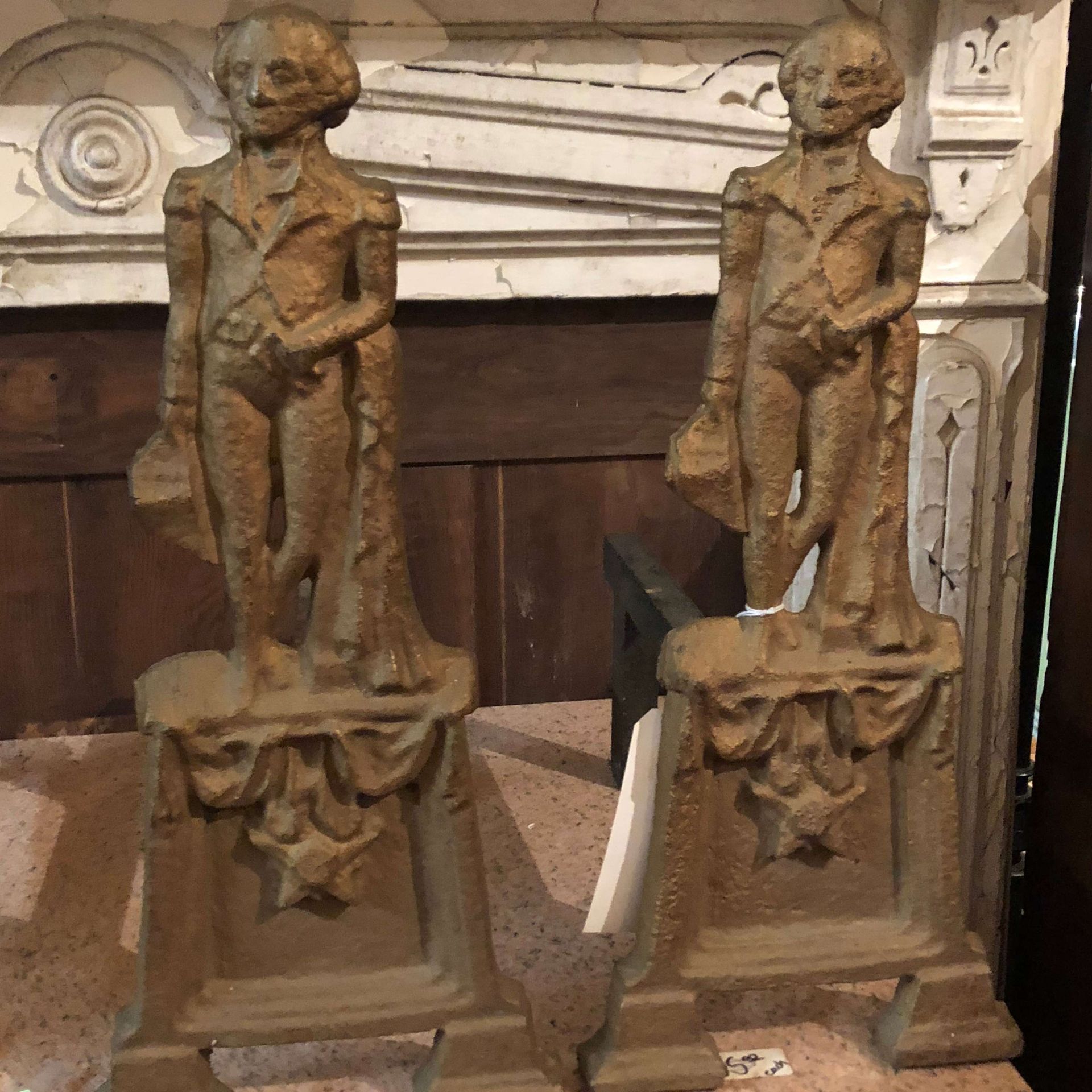 Two carved wooden skeleton statues standing on pedestals in a dim indoor setting