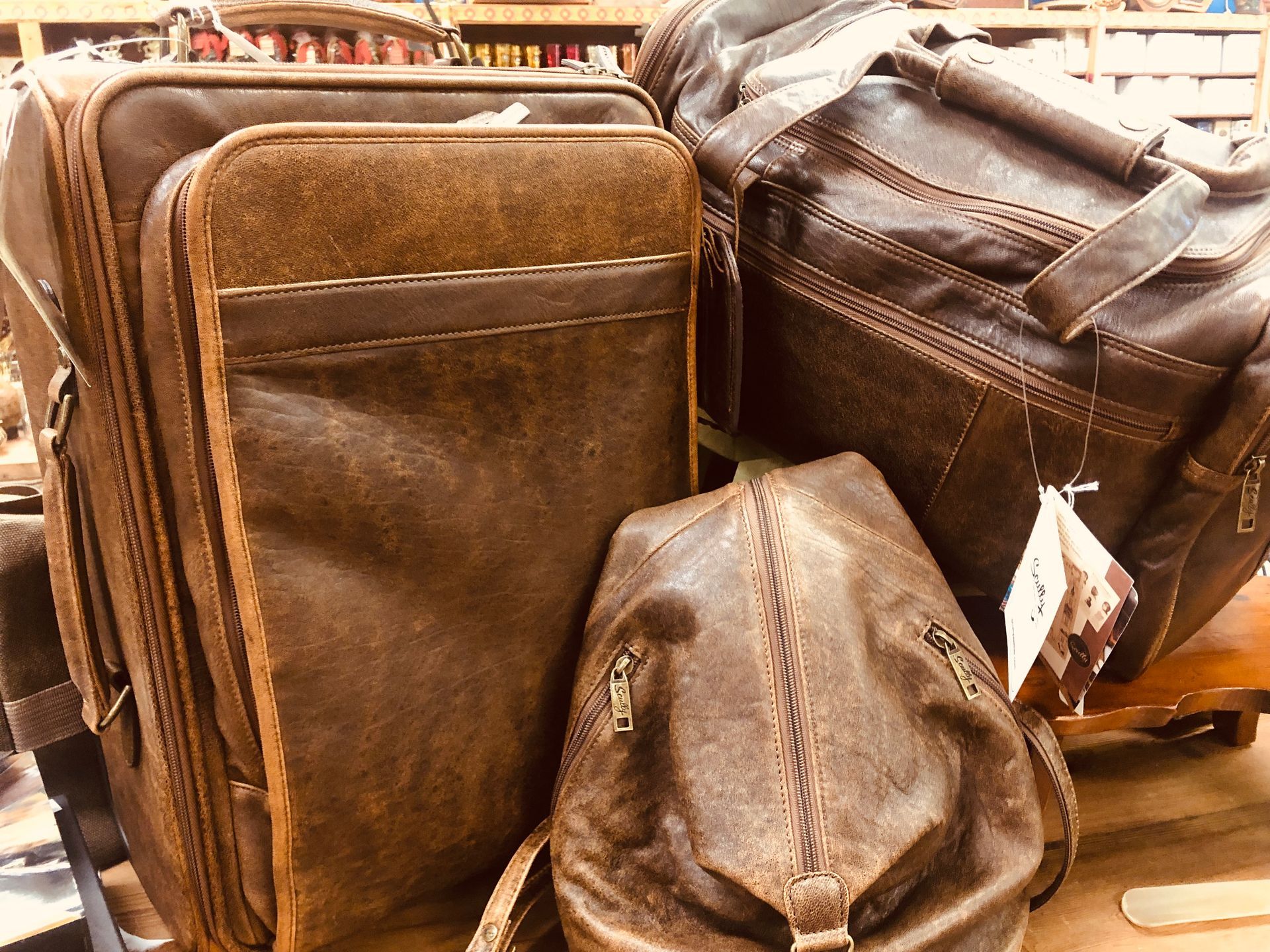 Brown leather bags displayed on a store shelf, including a backpack and zippered cases