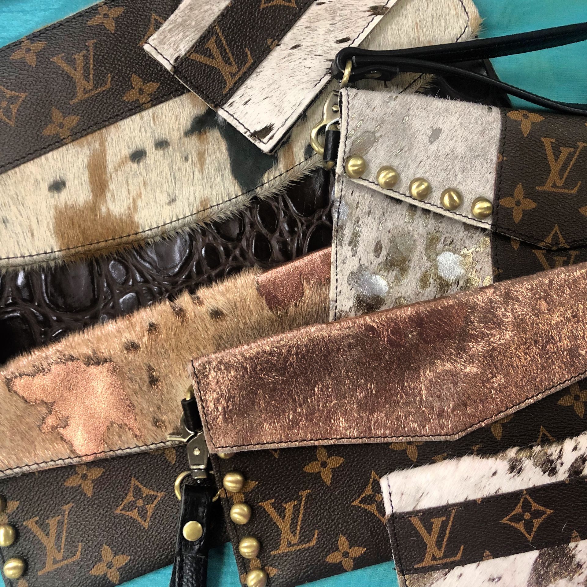 Assorted patterned designer wrist straps with metal studs and zippers in brown, tan, and black.
