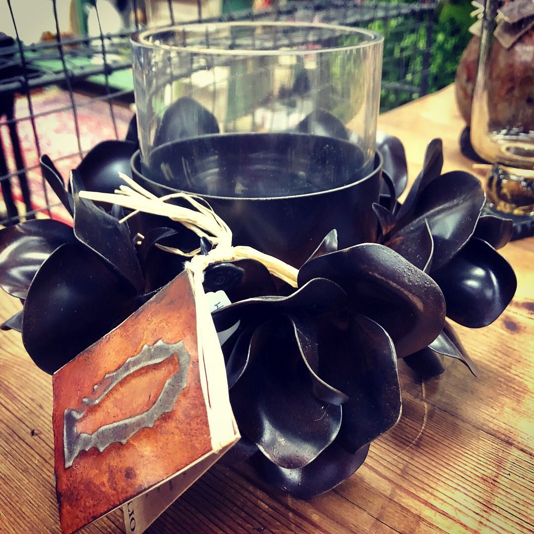 Black flower garland on a wooden table beside a glass candle holder and hanging tag