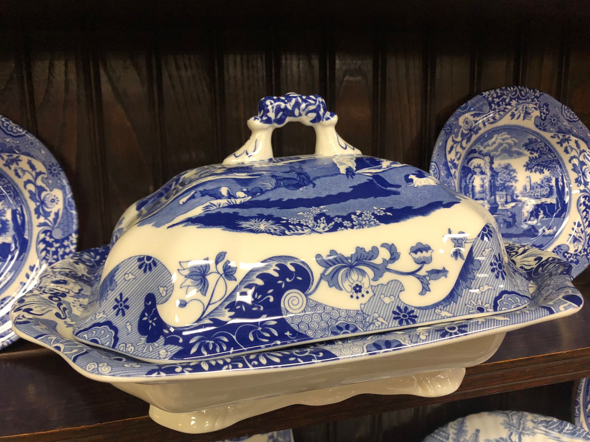 Blue-and-white porcelain covered serving dish with matching plates on a shelf