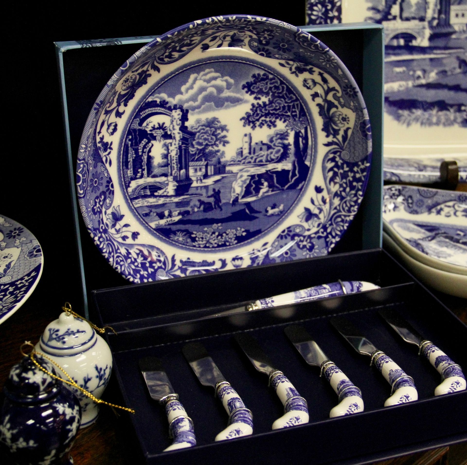Blue-and-white porcelain tea set in a display case, featuring a large decorative plate and matching utensils