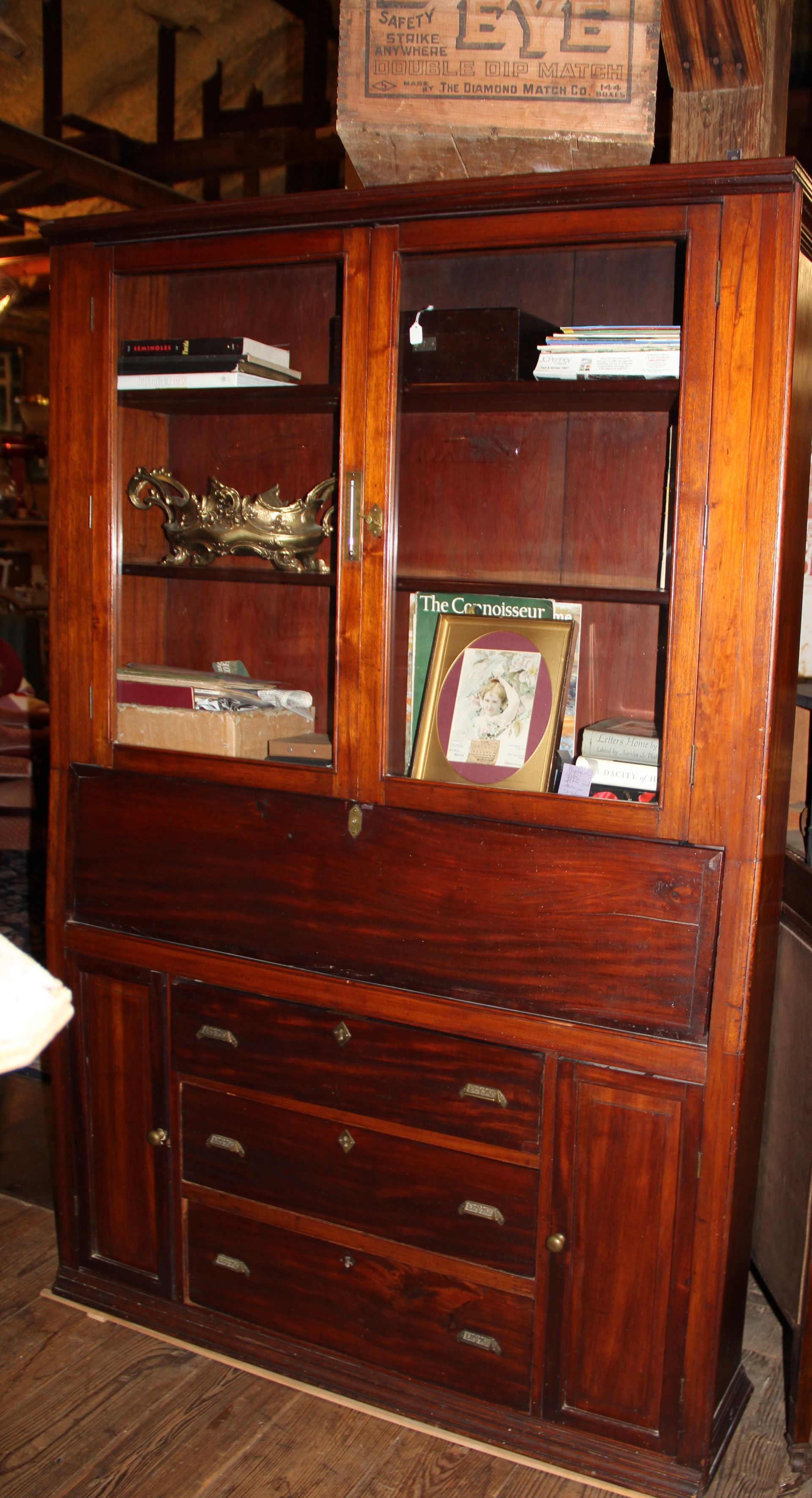 Tall dark wooden cabinet with glass doors and drawers in a room