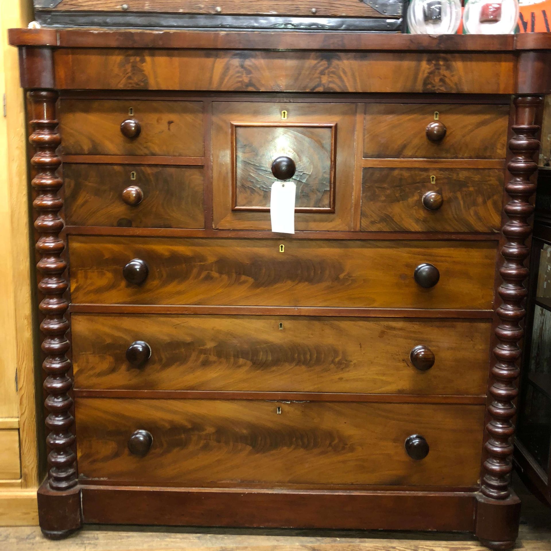 Antique wooden dresser with five drawers and a central lock, topped by two small decorative items.