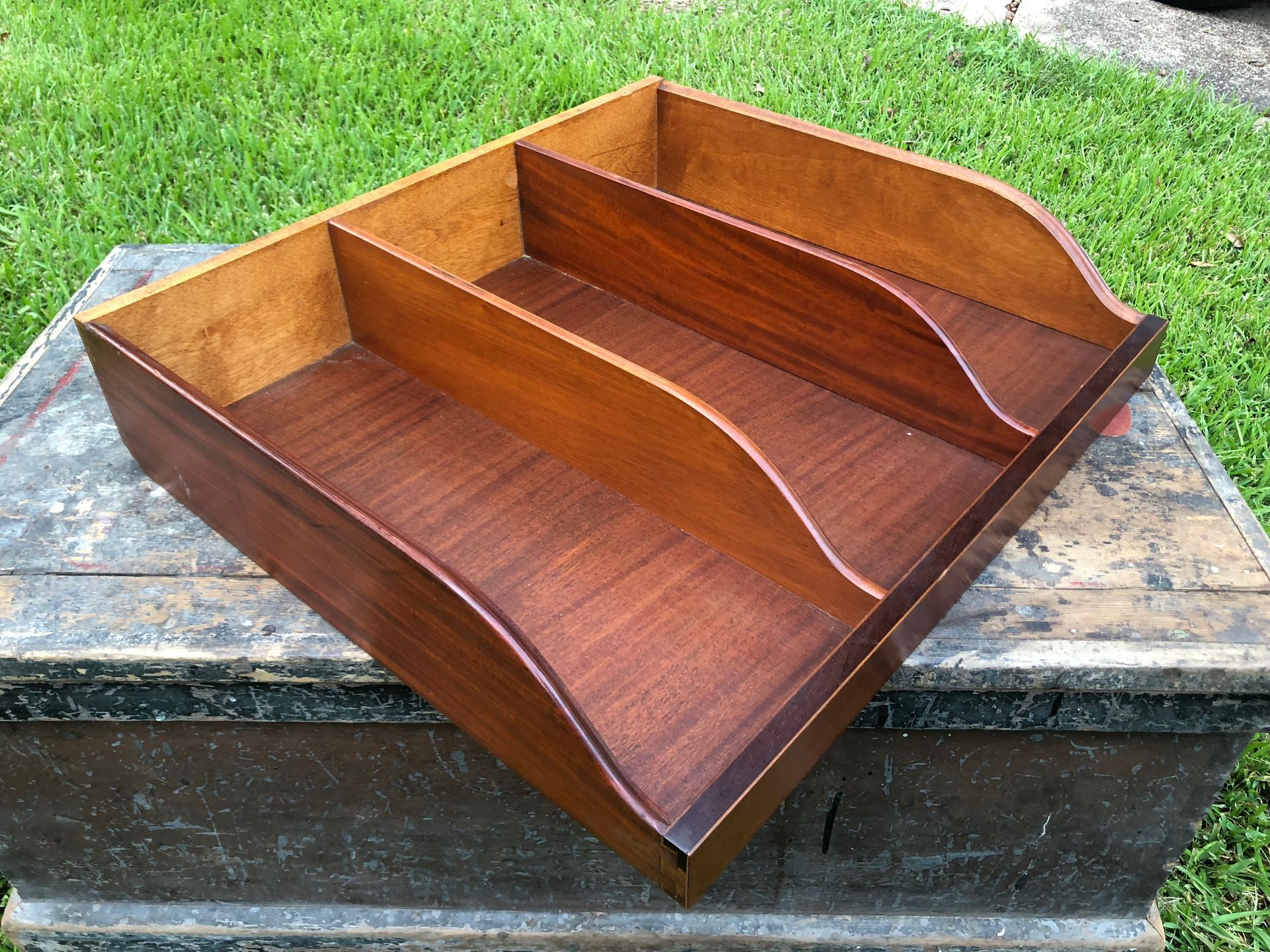 Wooden desk organizer tray with three compartments on a weathered outdoor table