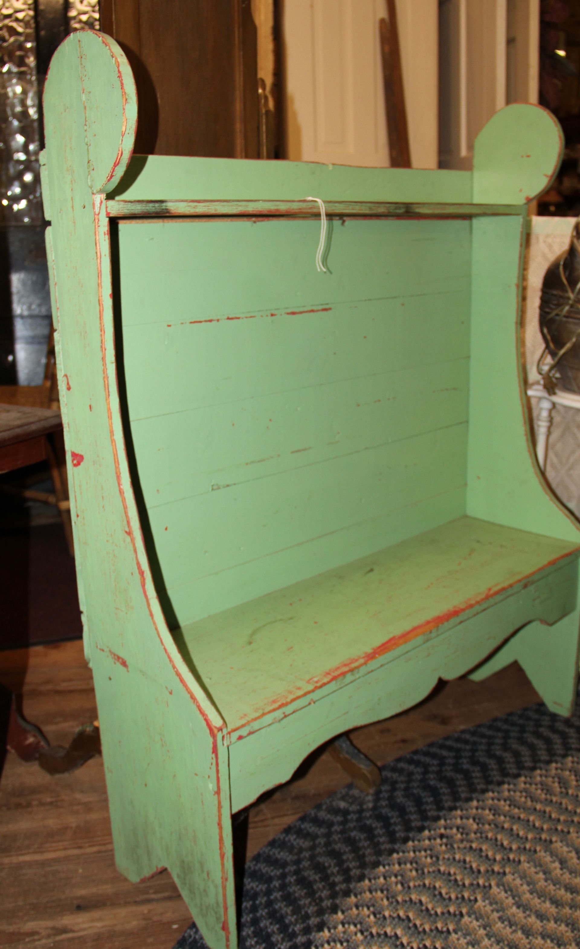 Mint green wooden bench with curved sides and a backrest, shown indoors on a rug.