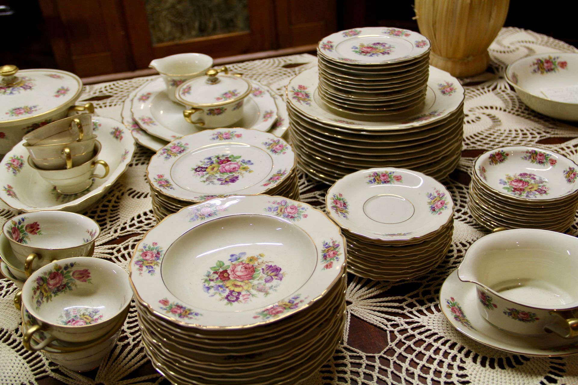 Stacks of floral china dishes and teacups arranged on a lace-covered table