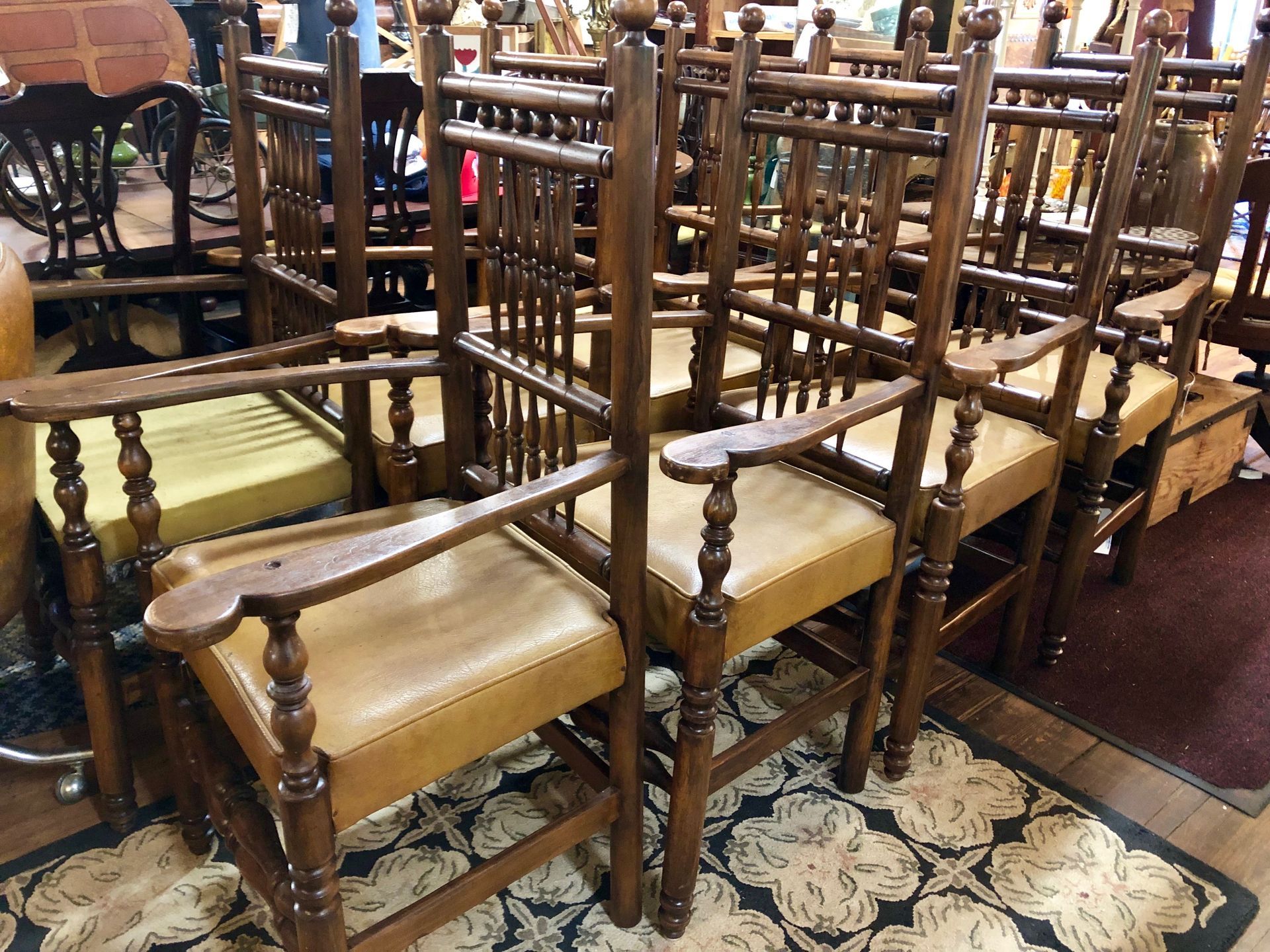 Rows of wooden chairs with tan cushions arranged on patterned rugs in a room