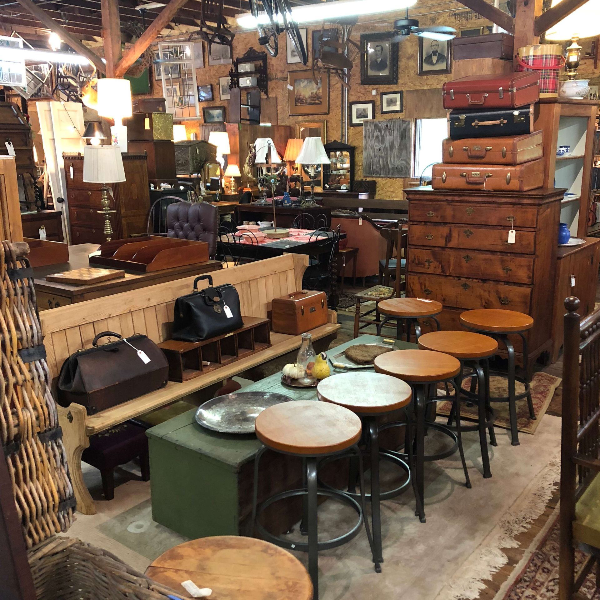 Cozy antique shop interior with wooden furniture, stools, lamps, and vintage decor.