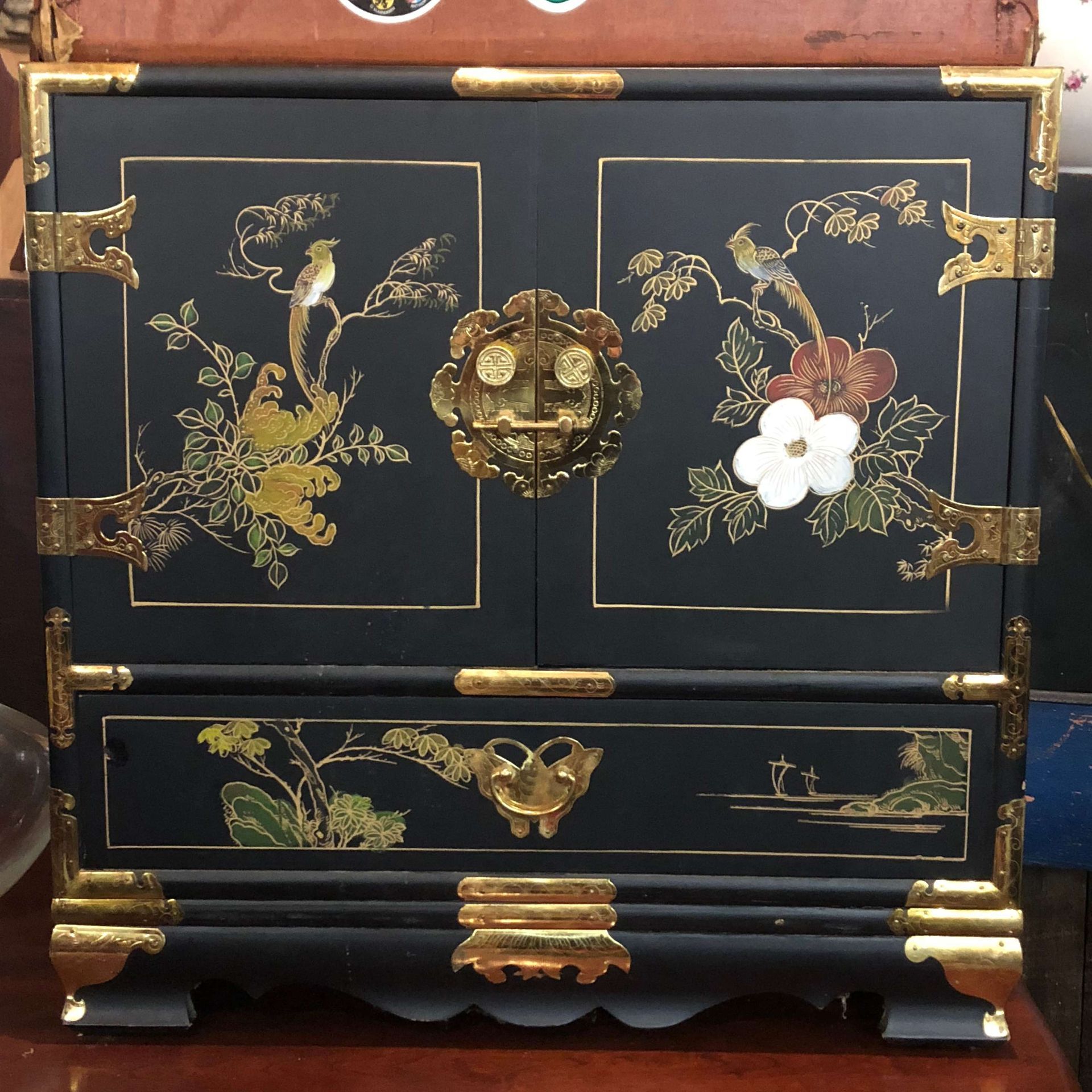 Black lacquered decorative chest with gold floral inlay and brass hardware, front view