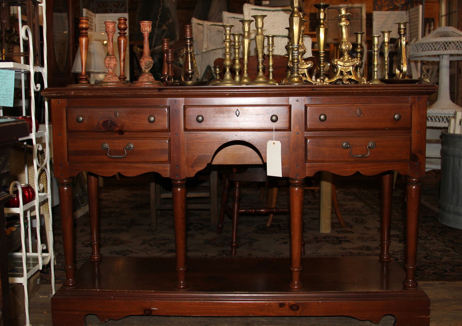 Antique wooden sideboard with brass candlesticks and decorative items on top in a dim room