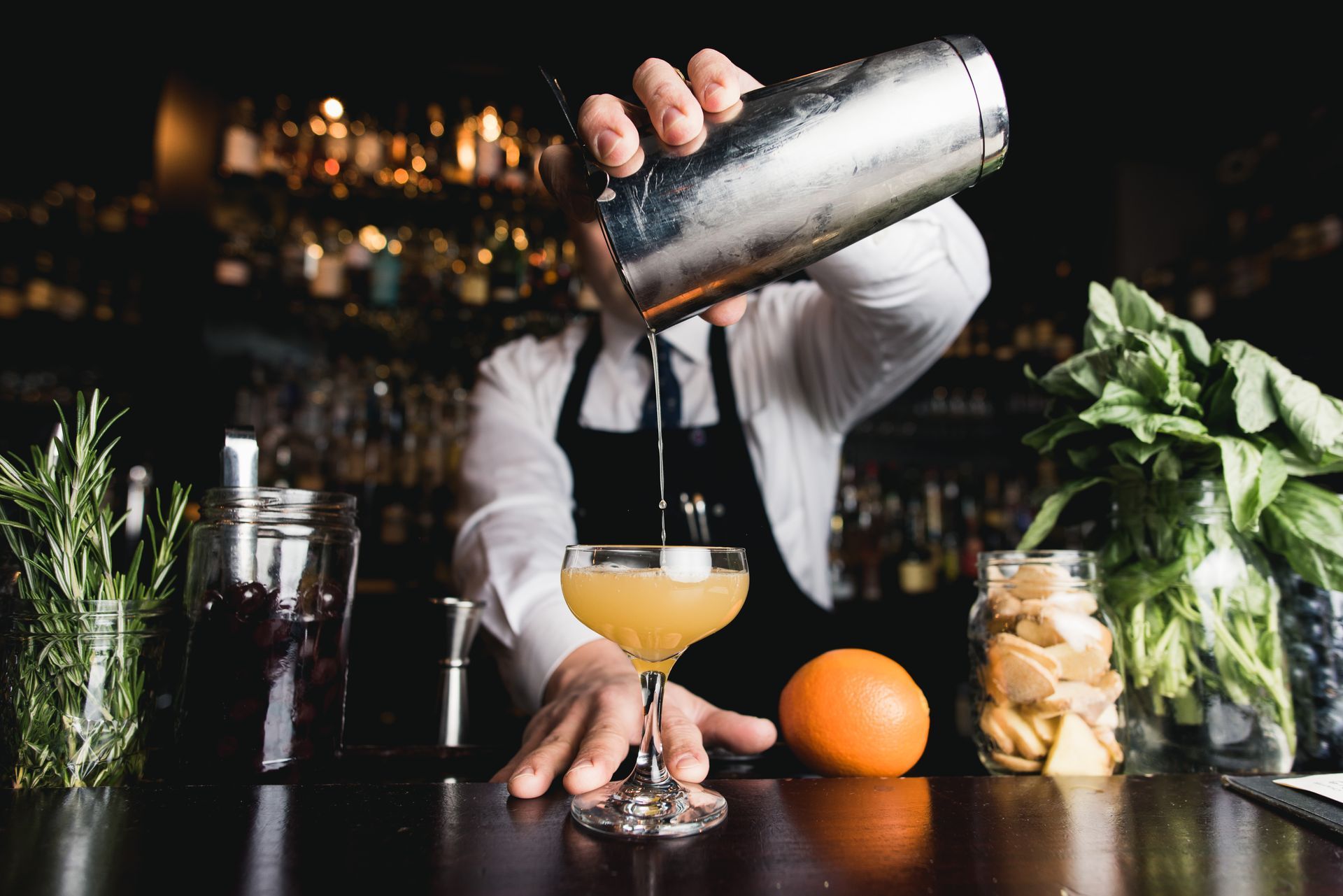 A bartender is pouring a drink into a glass.