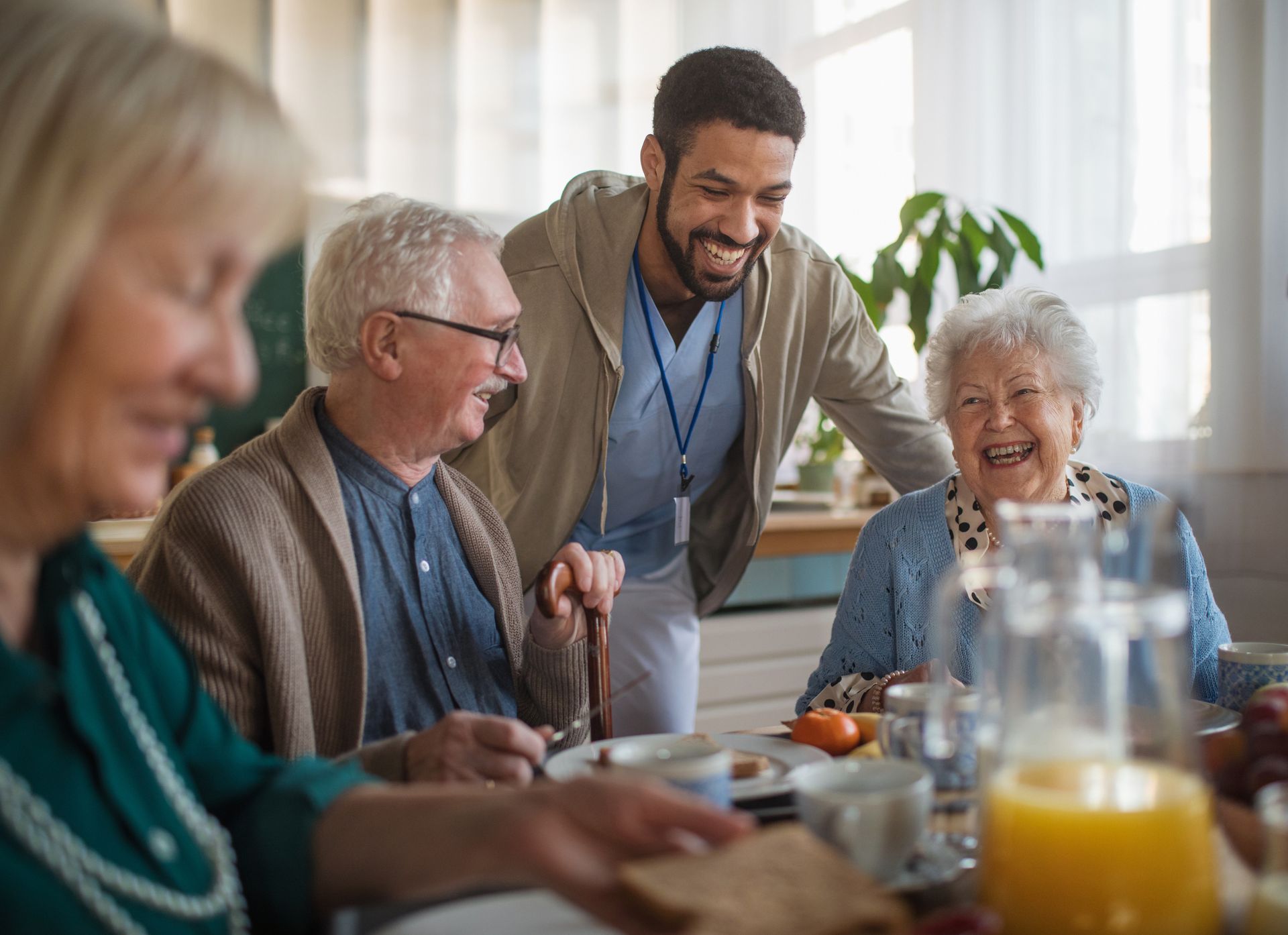 A man is standing next to a group of elderly people sitting at a table.