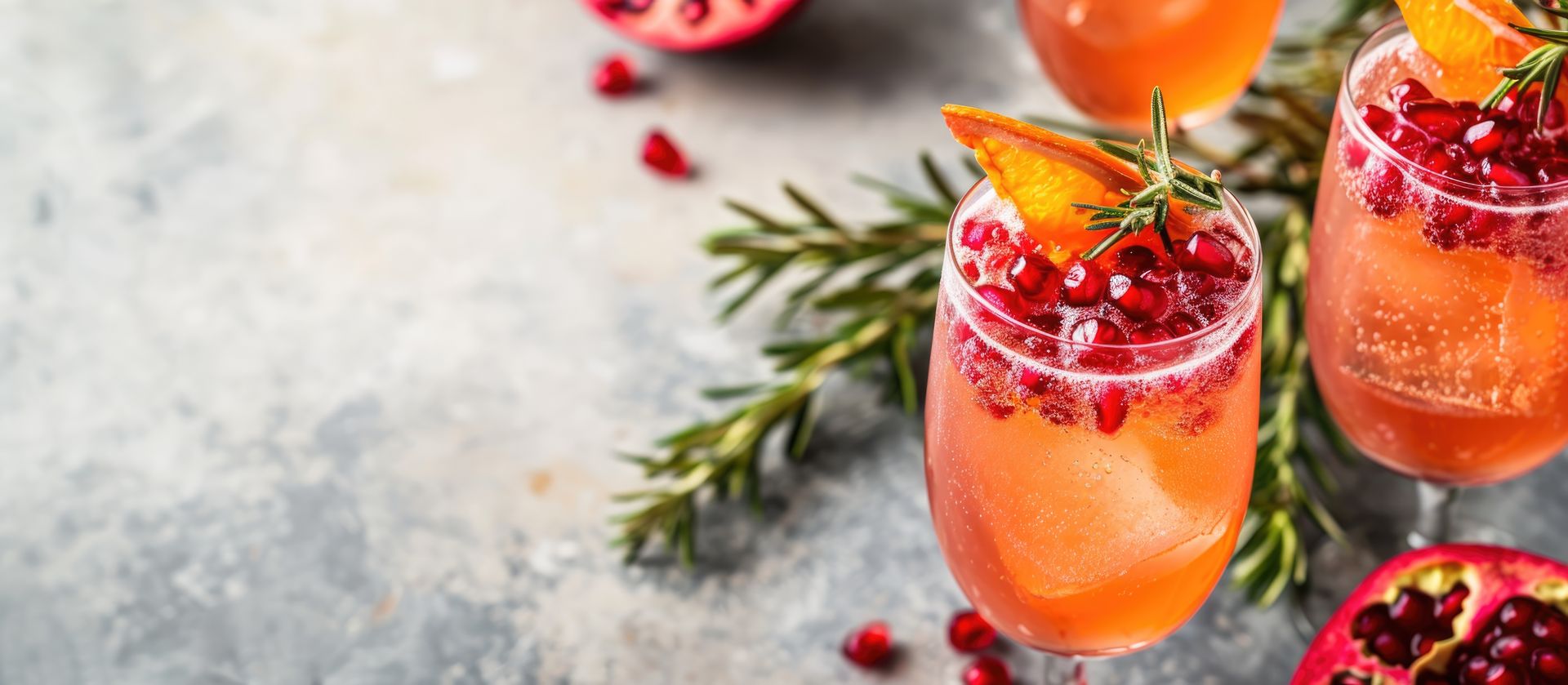 A close up of three glasses of a drink with pomegranate seeds on a table.