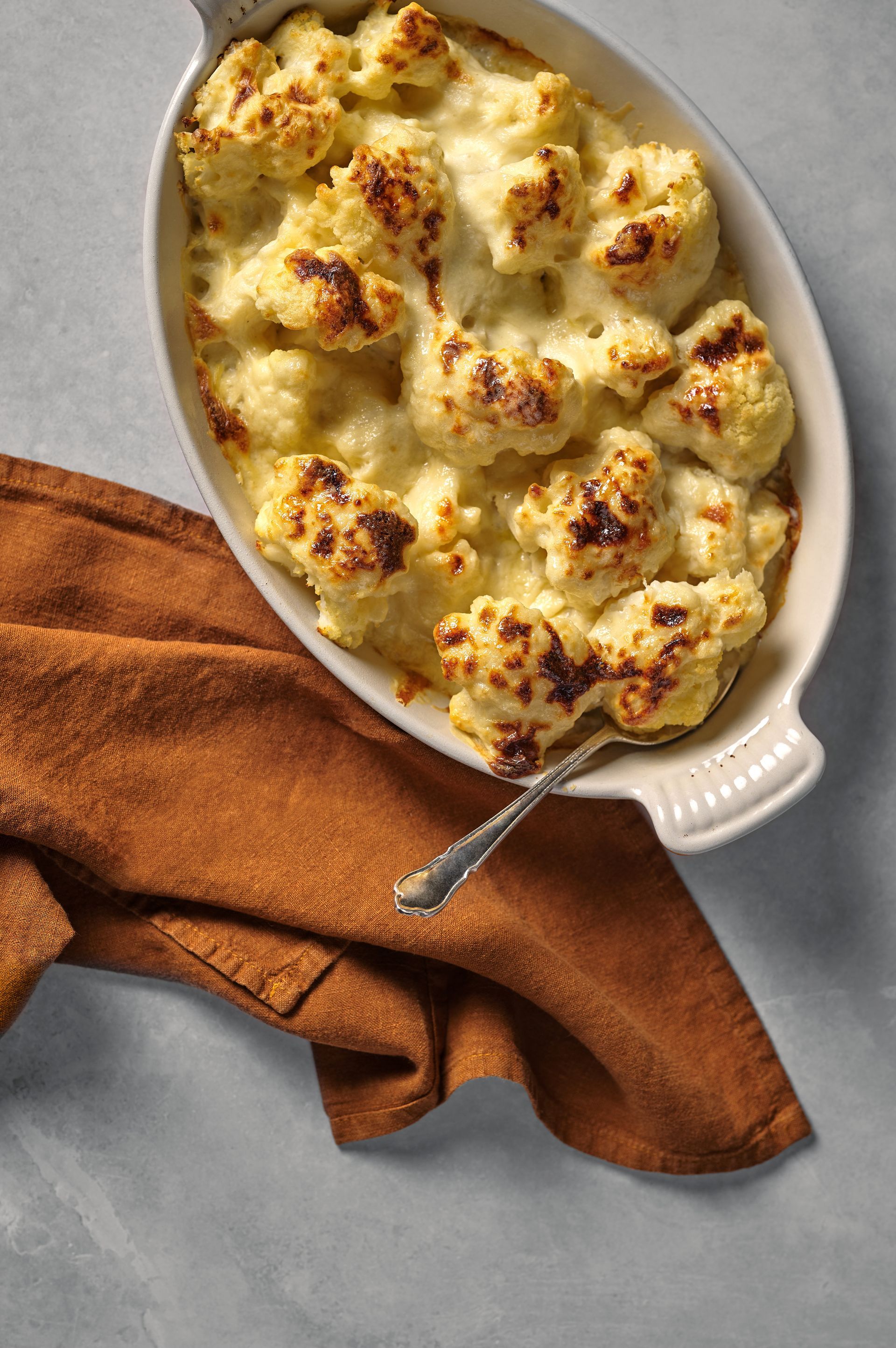 A casserole dish filled with cauliflower and cheese with a fork in it.