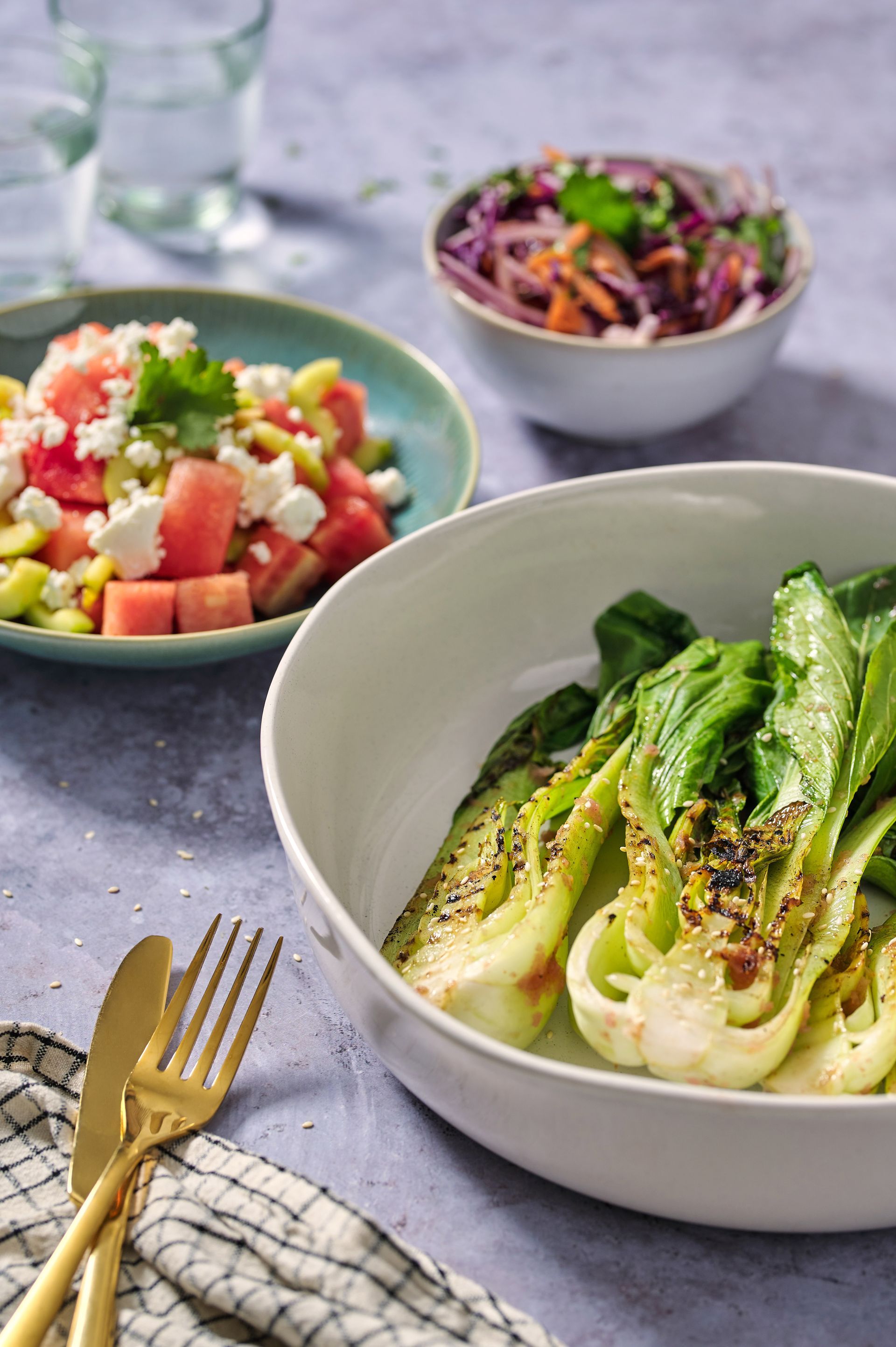 A bowl of lettuce is sitting on a table next to a bowl of salad.