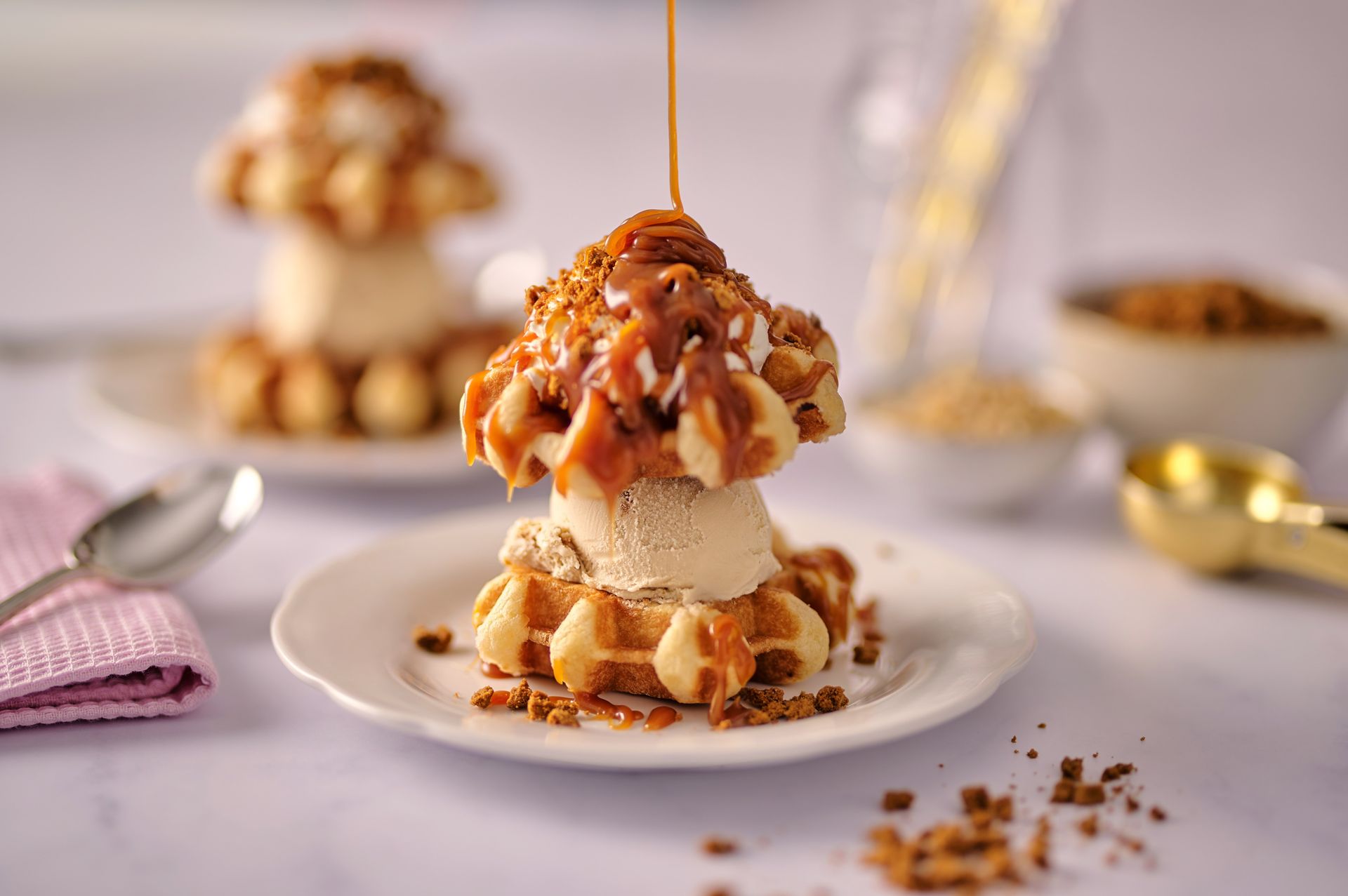 A waffle with ice cream and caramel sauce on top of it on a plate.