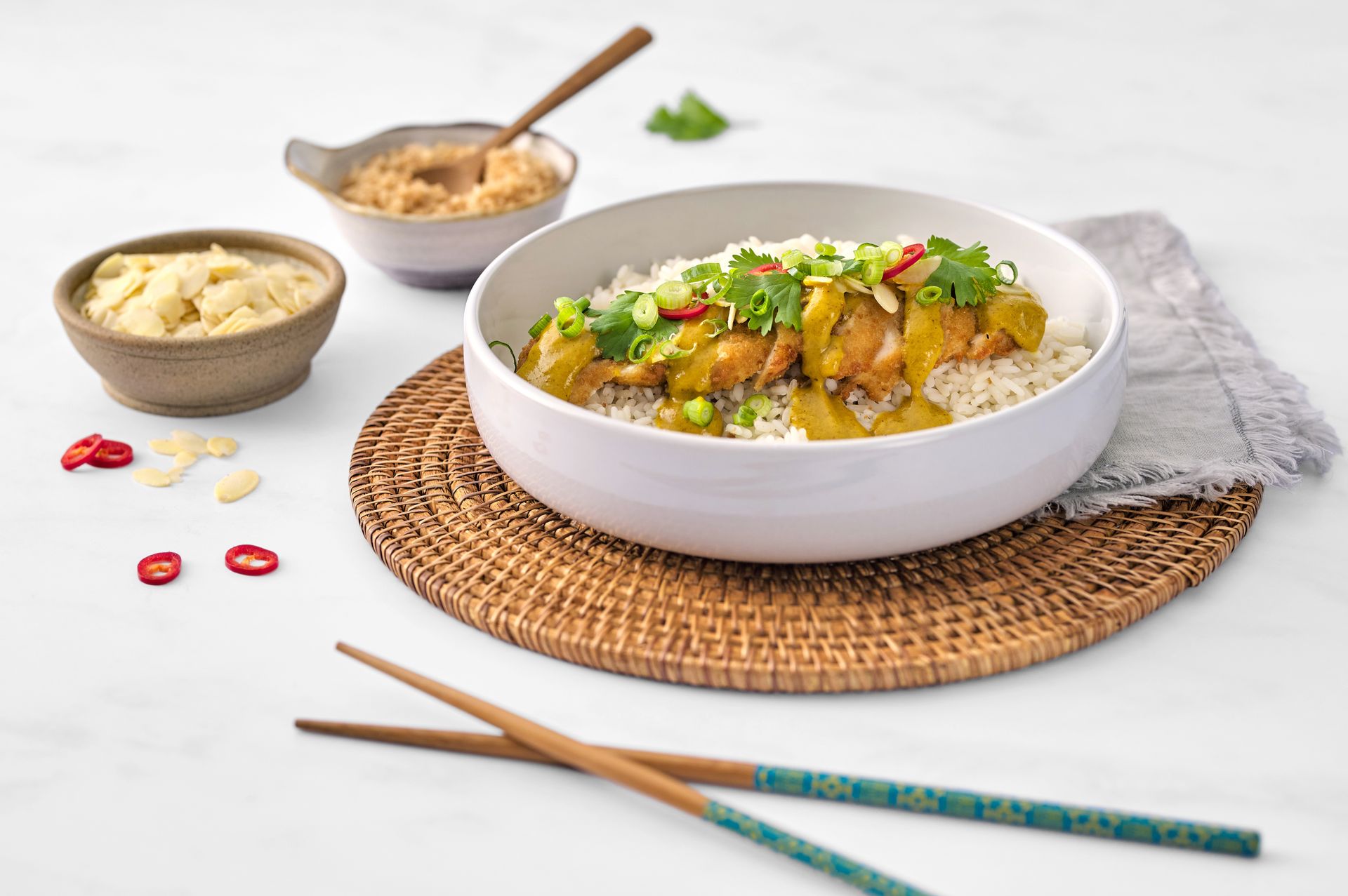 A bowl of food with chopsticks on a place mat on a table.