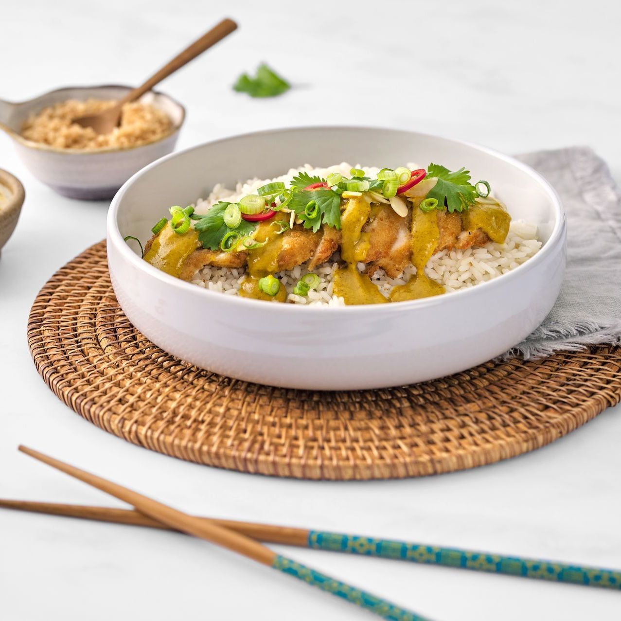 A bowl of food with chopsticks on a place mat