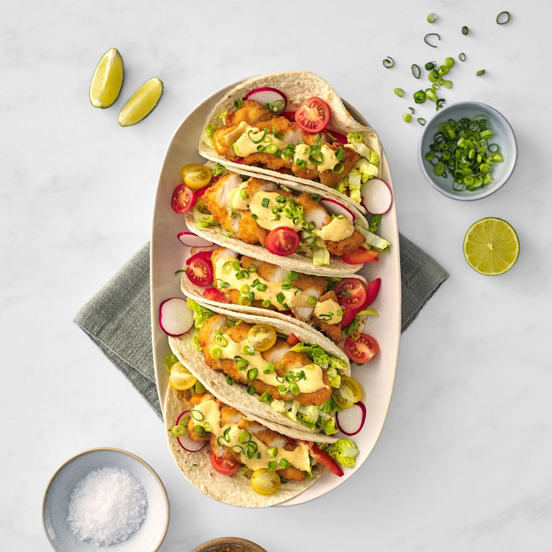 A white plate topped with tacos and vegetables on a table.
