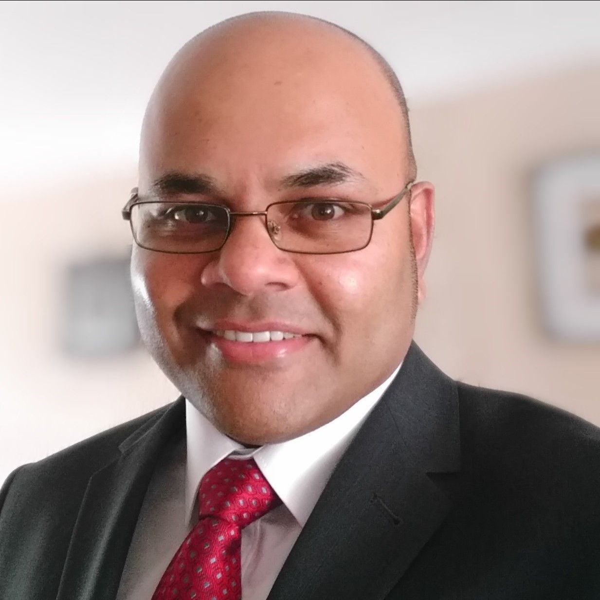 A bald man wearing glasses and a suit and tie