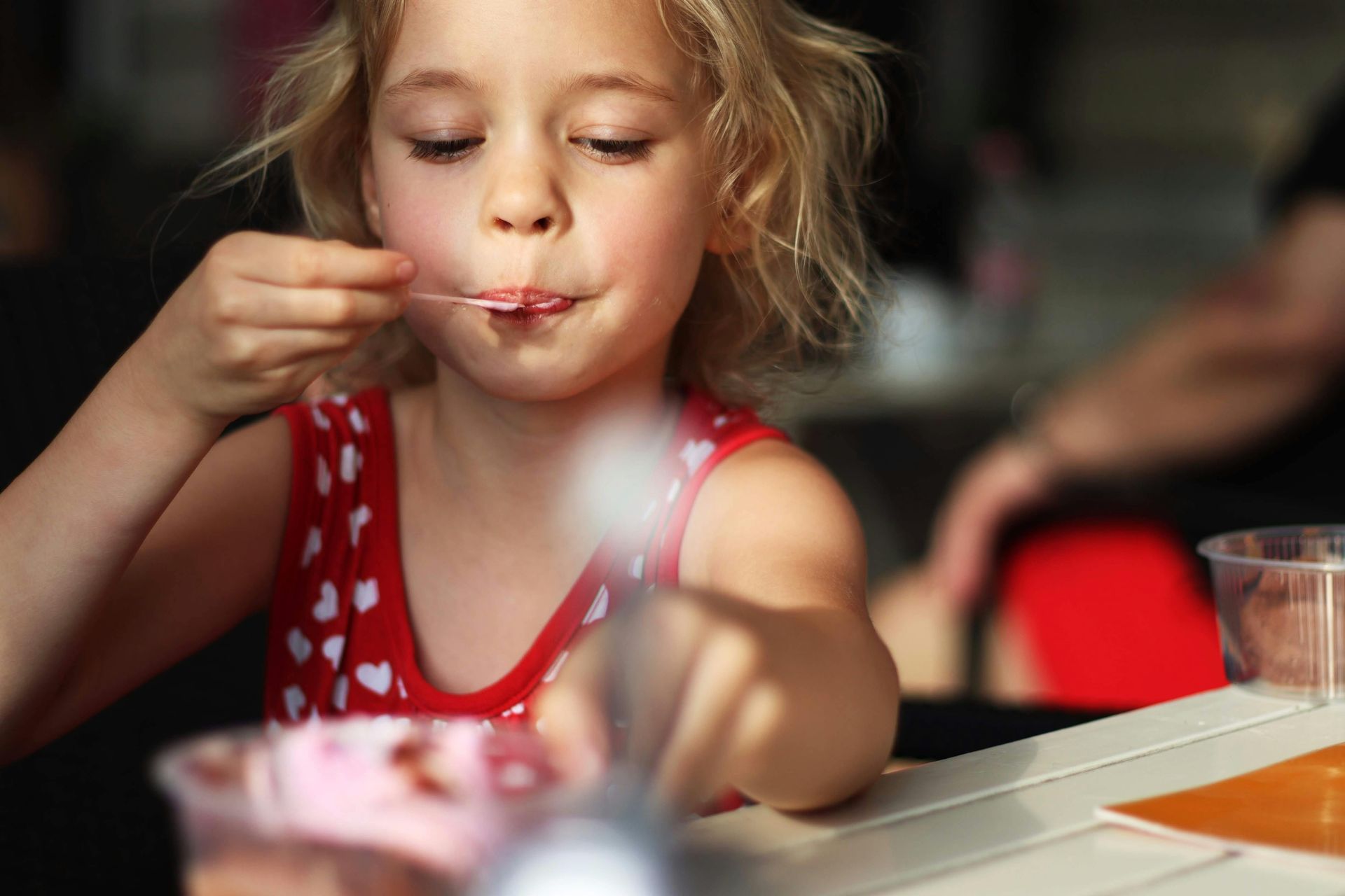 A little girl is eating ice cream with a spoon.